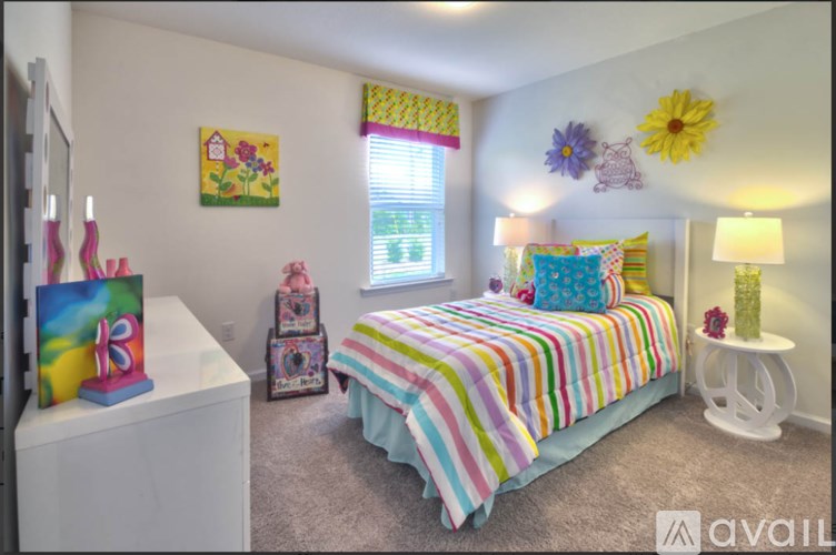 A bedroom with a colorful bed and a painting on the wall.