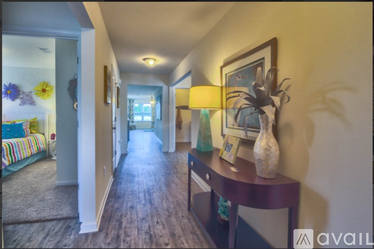 A hallway with a bed on the left and a vase on a table on the right.