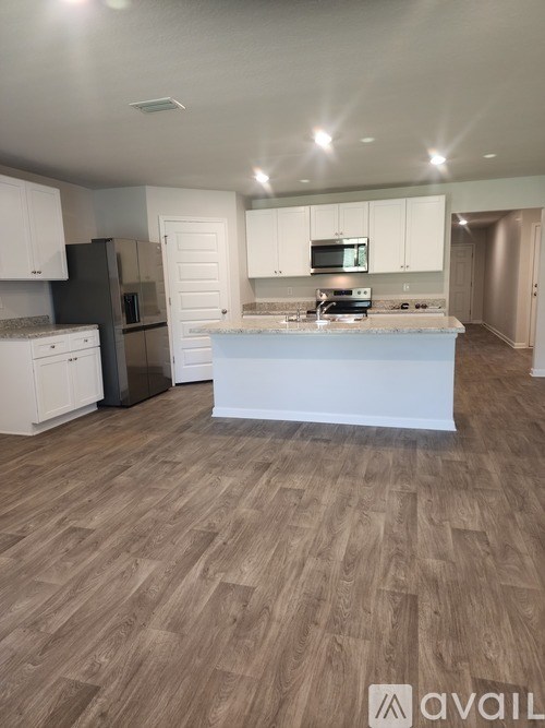 A kitchen with a white countertop and wooden flooring.