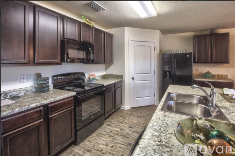 A kitchen with brown cabinets and a black refrigerator.
