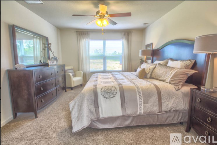 A bedroom with a large bed, a dresser, and a ceiling fan.