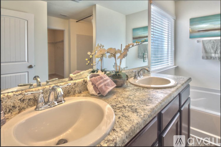 A bathroom with a sink, mirror, and a vase with dried flowers.