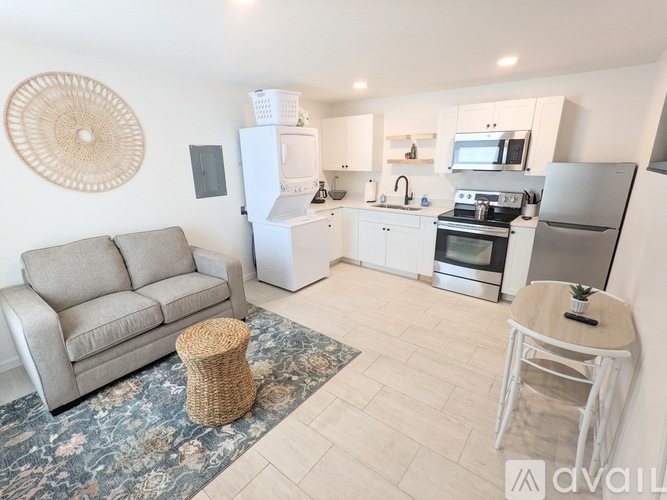 A modern kitchen with a grey sofa and a woven ottoman.