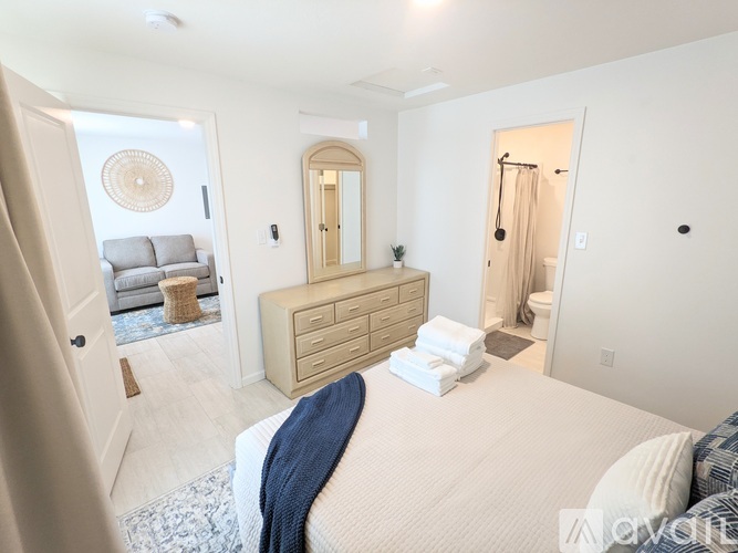 A bedroom with a large bed and a dresser with a mirror above it.