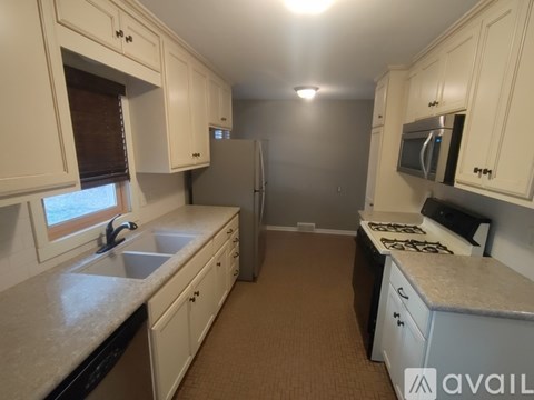 A kitchen with white cabinets and a refrigerator.