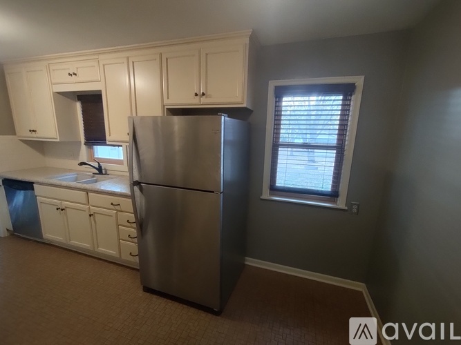 A kitchen with a refrigerator, sink, and cabinets.