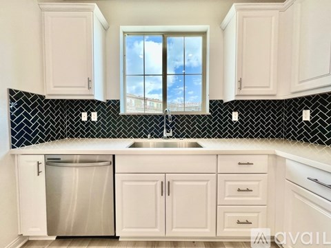 A kitchen with white cabinets and a black and white tiled backsplash.