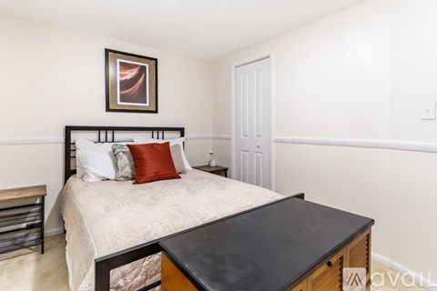 A bedroom with a bed, nightstand, and a painting on the wall.