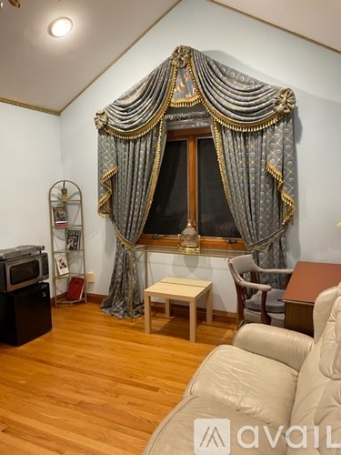 A living room with a large window dressed with a grey curtain and a golden curtain.