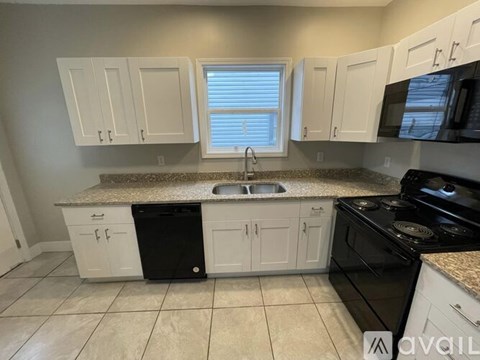 A kitchen with white cabinets and black appliances.