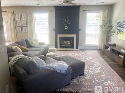 A living room with a grey couch and a fireplace.