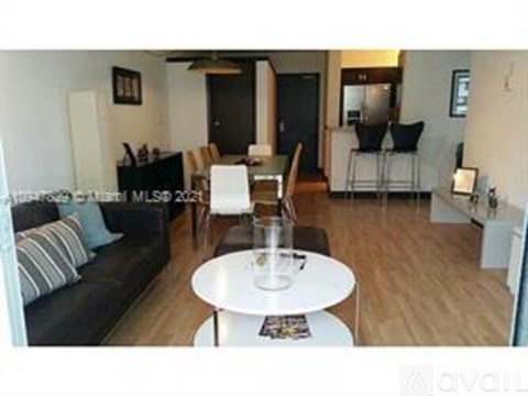 A living room with a black couch and a white coffee table.