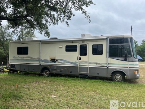 A silver RV is parked in a grassy field.