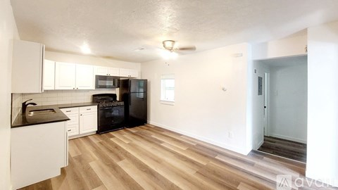 A kitchen with white cabinets and black countertops.