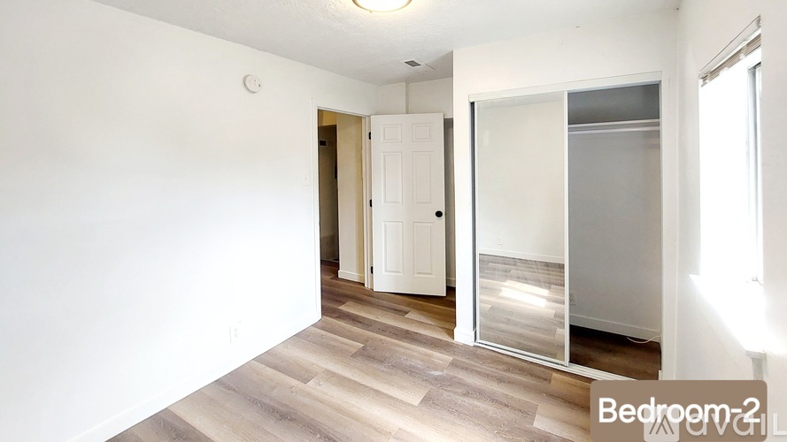 A white bedroom with a wooden floor and a white door.