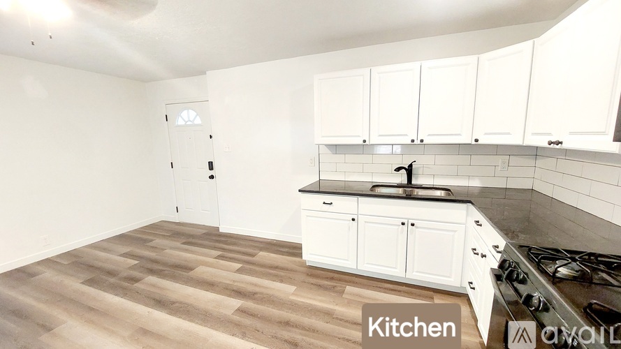 A kitchen with white cabinets and a wooden floor.