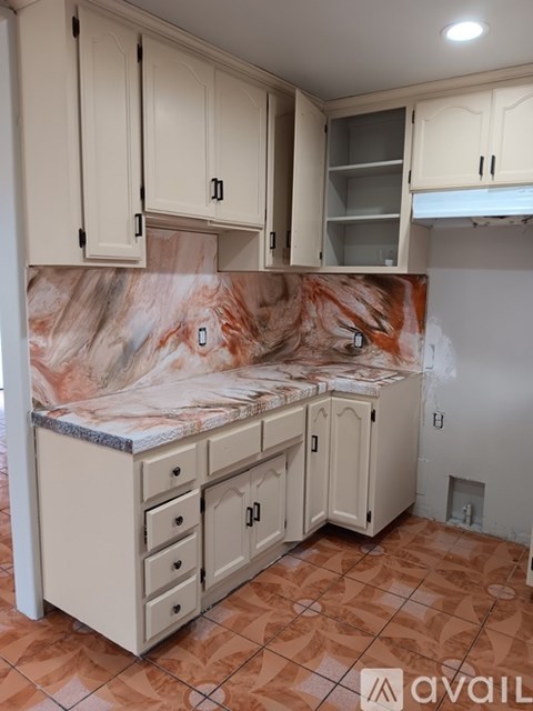 A kitchen with marble countertops and white cabinets.