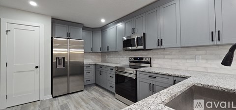 A kitchen with a stainless steel refrigerator and a marble countertop.