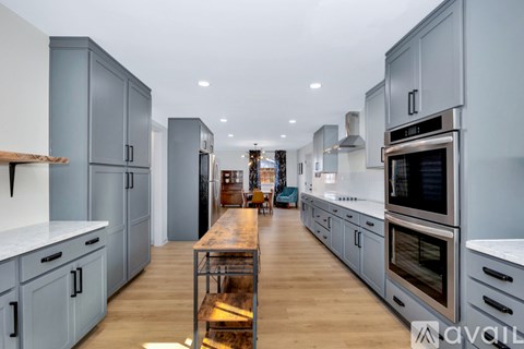 A modern kitchen with a long wooden table and stainless steel appliances.