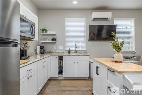 A kitchen with white cabinets and a wooden countertop.