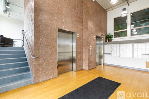 A hallway with a brick wall and two elevators.
