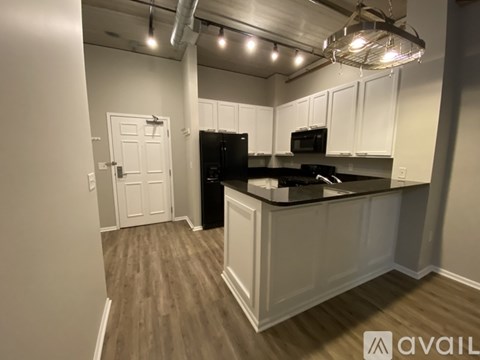 A kitchen with white cabinets and a black fridge.