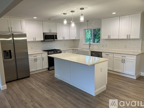 A kitchen with white cabinets and a wooden island.