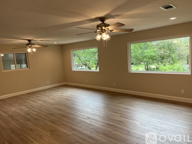 A spacious room with a ceiling fan and hardwood flooring.