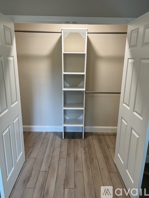 A white ladder is leaning against a wall in a room with wooden flooring.