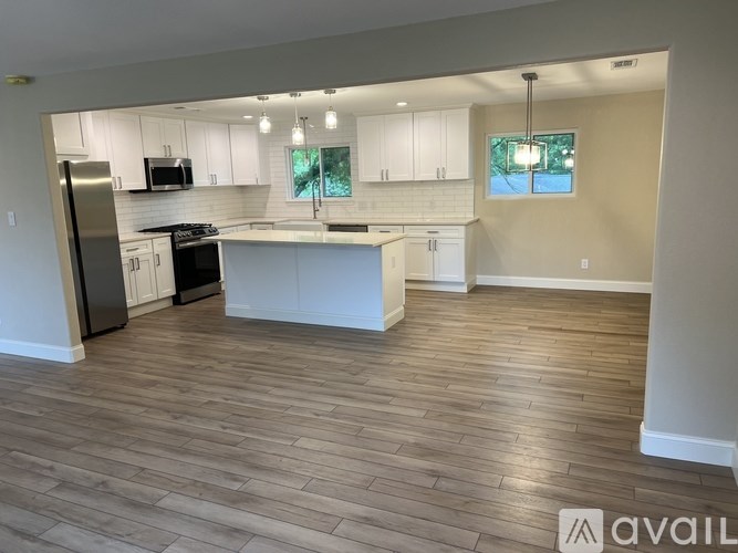 A kitchen with a refrigerator, microwave, and stove top oven.