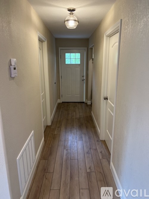 A long hallway with wood floors and white walls.