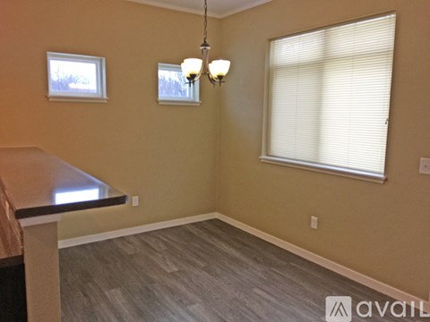A room with a table, two windows, and a chandelier.