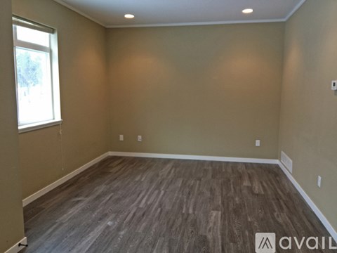 A room with wooden flooring and a window on the left side.