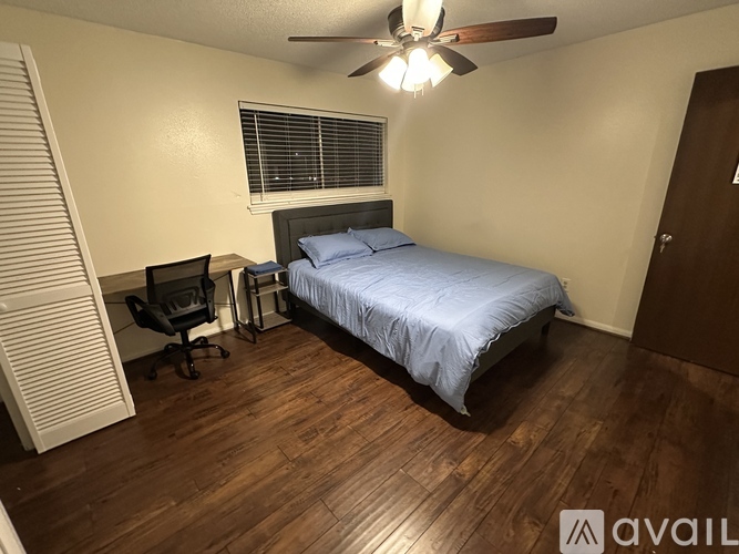 A bedroom with a bed, desk, and chair.