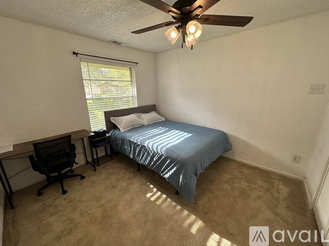 A bedroom with a bed, desk, and chair.