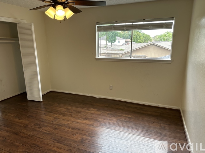 A bedroom with a bed, desk, and window.