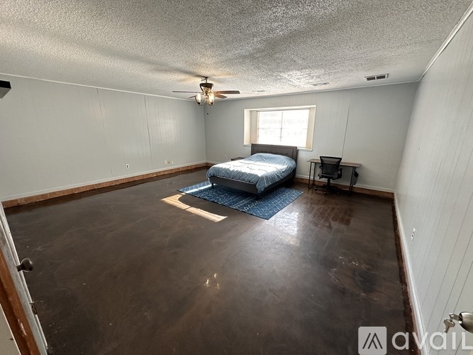 A bedroom with a bed, desk, and window.