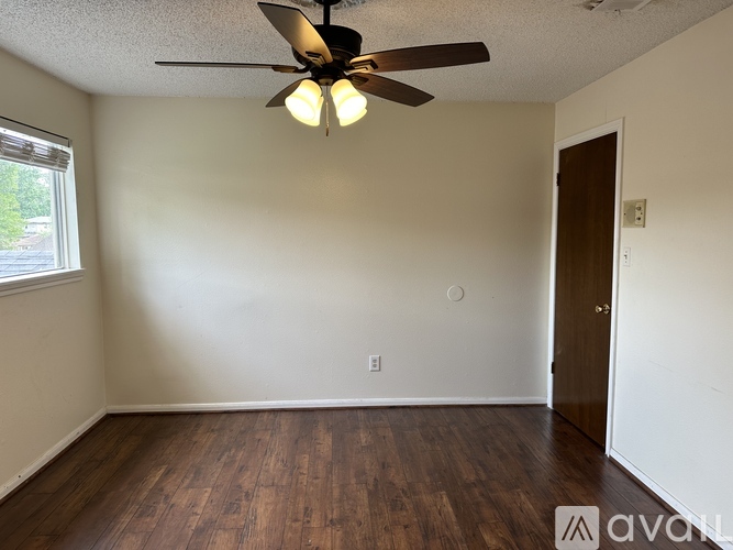 A bedroom with a bed, a ceiling fan, and a wall-mounted shelf.