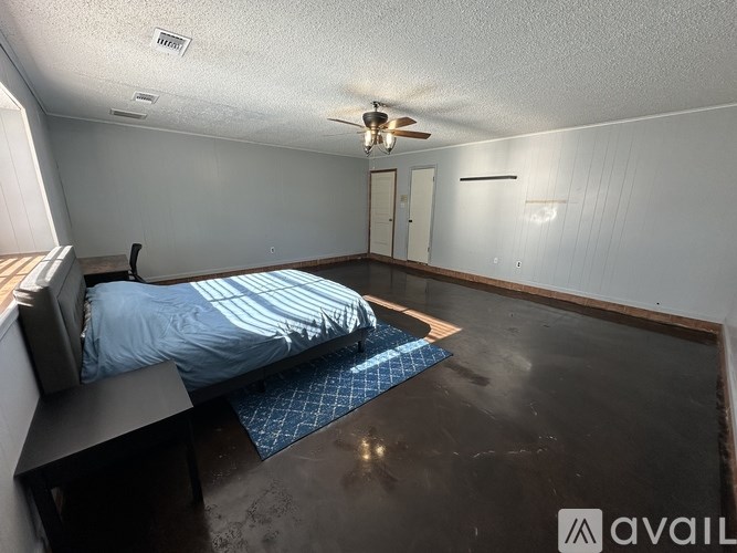 A bedroom with a bed, a ceiling fan, and a wall-mounted shelf.