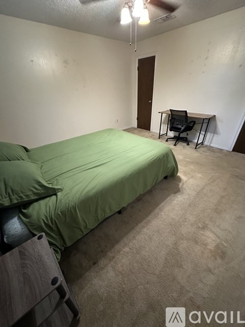 A bedroom with a bed, a ceiling fan, and a wall-mounted shelf.
