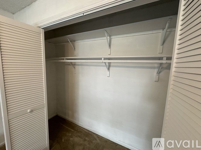 A white closet with a shelf and a door.