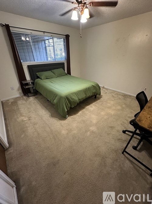 A bedroom with a bed, chair, and ceiling fan.