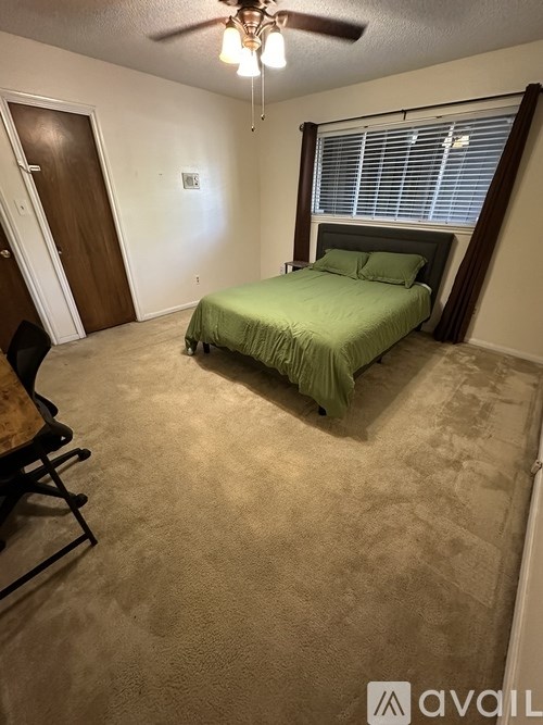 A bedroom with a bed, chair, and ceiling fan.