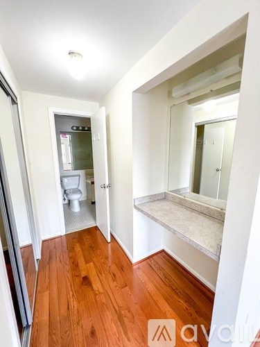A hallway with a toilet visible through the door.