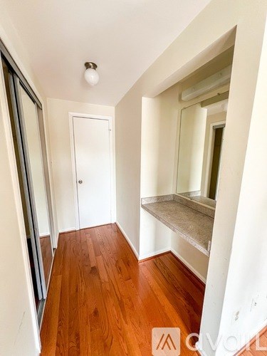 A hallway with wood flooring and white walls.