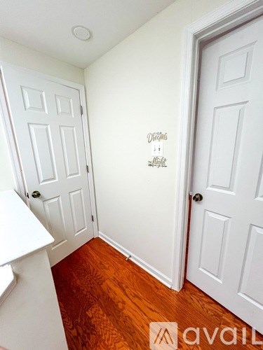 A white door with a wall decal that says "Divine Light" is in a room with wooden floors.