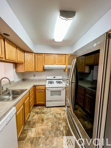 A kitchen with wooden cabinets and a white stove top oven.