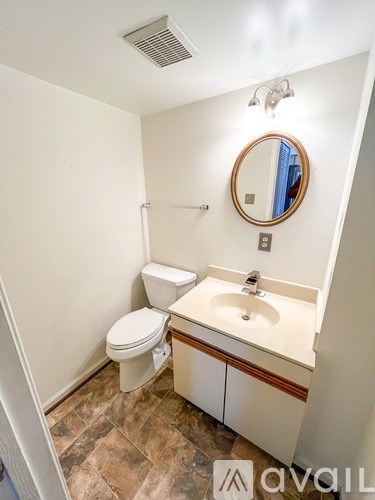 A bathroom with a toilet, sink and mirror.