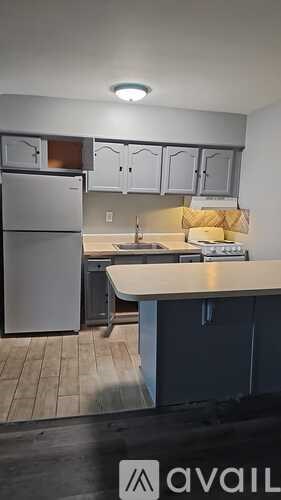 A kitchen with a refrigerator, cabinets, and a counter.