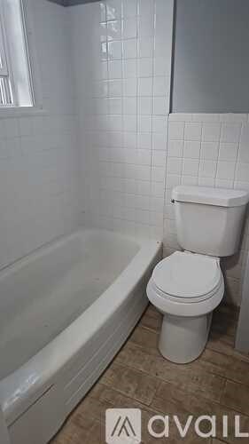 A white toilet sits next to a bathtub in a bathroom.